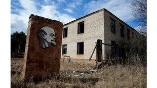 Un panel con un retrato de Lenin y un edificio abandonado se ven en la zona de exclusión de 30 km alrededor del reactor nuclear de Chernobyl en la aldea abandonada de Orevichi, Bielorrusia