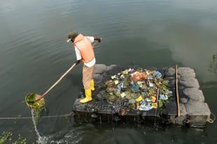 Un trabajador recoge basura de un lago en las afueras de Colombo, Siri Lanka