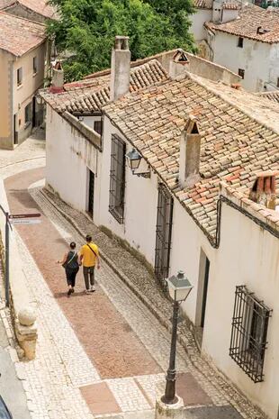 Turistas caminan por la Calle de Benito Hortelano, entre tejados y veredas adoquinadas.