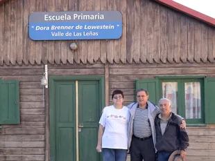 Tito Lowenstein junto a Elsa Karam, histórica empleada del valle, y Luis "Yiyo" Ballarini, director del Museo Las Leñas, frente a la escuela primaria que lleva el nombre de su madrina, Dora Brenner de Lowenstein, madre de Tito.
