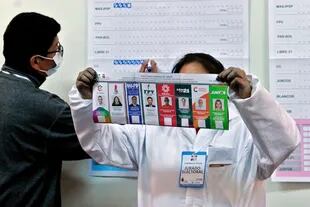 Un empleado electoral muestra una papeleta mientras cuenta los votos en un colegio electoral durante las elecciones generales en La Paz