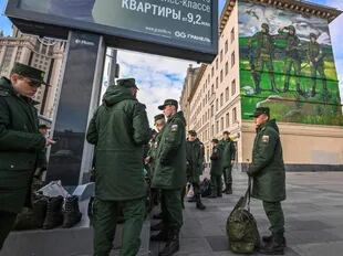 Soldados rusos esperan su salida mientras se encuentran cerca de un mural que representa a militares rusos con brazaletes con el símbolo "Z", cerca de la terminal ferroviaria de Paveletsky, en el centro de Moscú el 16 de octubre de 2022.