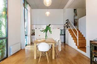 Bien sencilla, mesa de madera maciza diseñada por Martin y construida por un carpintero, acompañada por un juego de sillas blancas ‘Eiffel Dsw’ de Eames.