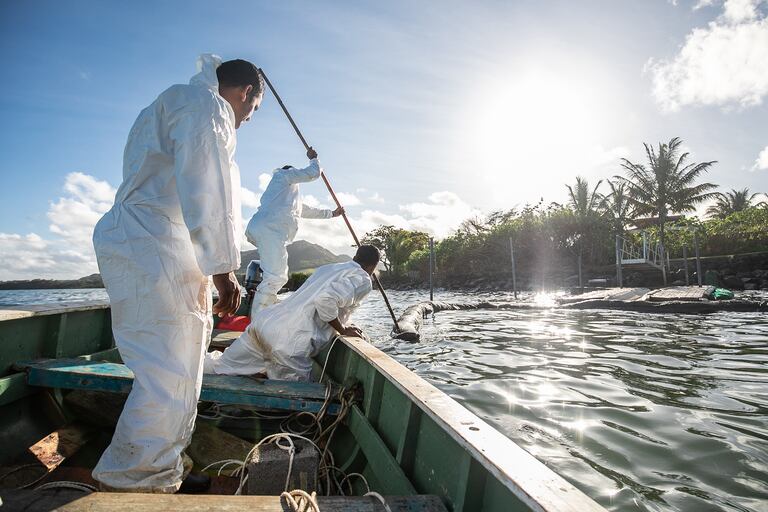 Los pescadores colocan barreras hechas a mano en el mar en el Viejo Gran Puerto de Mauricio el 11 de agosto de 2020 para bloquear el petróleo derramado del buque MV Wakashio