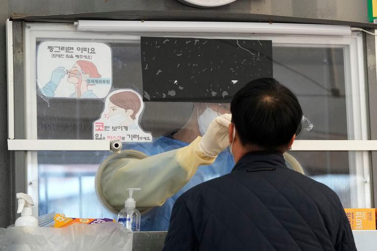Un trabajador médico hace un hisopado en Seúl, donde aumentaron las restricciones a los viajeros por la variante ómicron 
