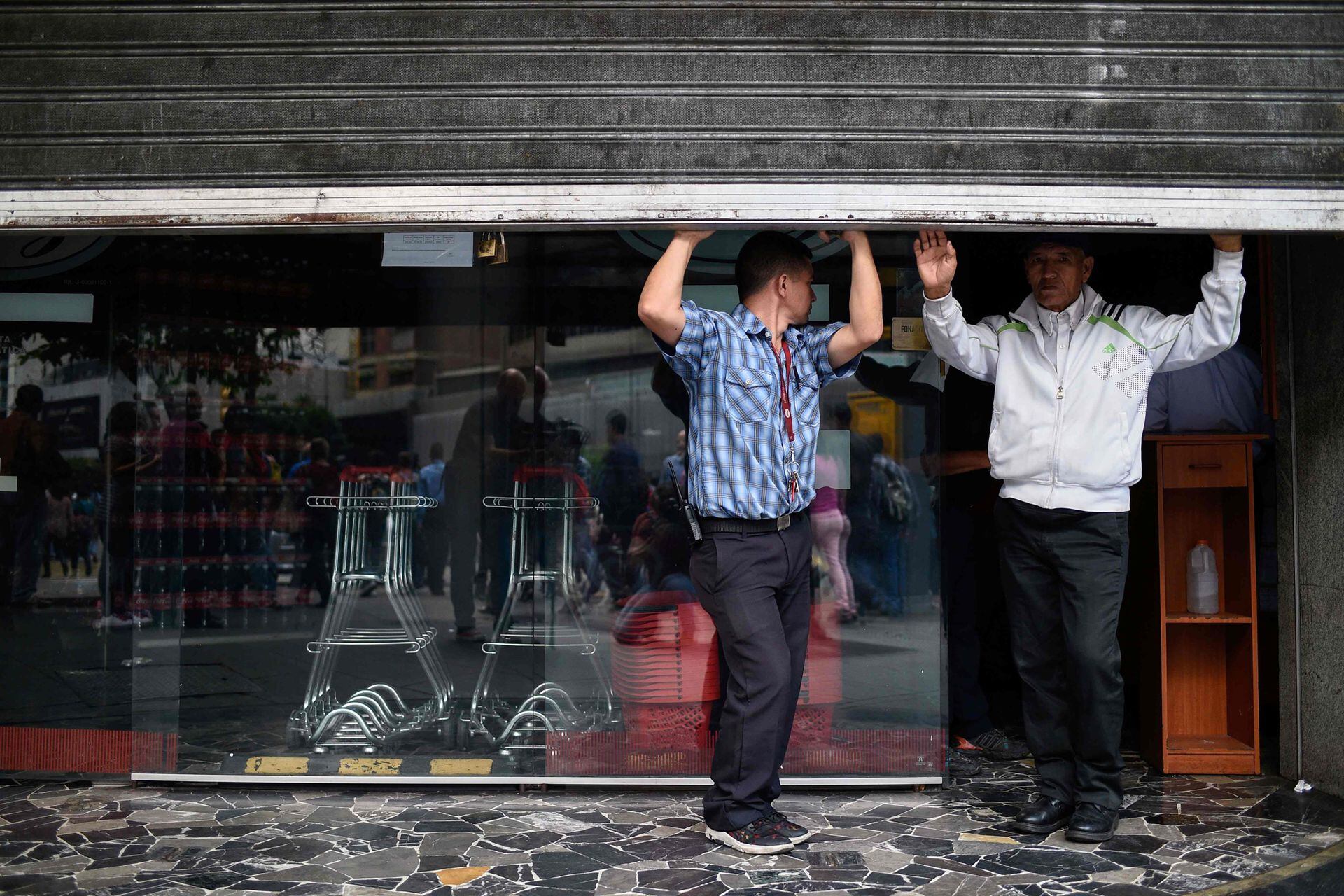 Los empleados están parados dentro de un supermercado, durante un corte de energía en Caracas el 7 de marzo de 2019.