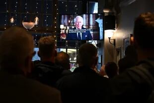 Un grupo de personas en el pub Príncipe de Gales en el centro de Londres ven un discurso televisado del rey Carlos III