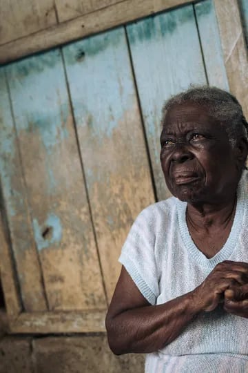 Agida Lucía, de 89 años, se sienta frente a su casa en la roca Agostinho Neto, una plantación de cacao abandonada de Santo Tomé y Príncipe el 29 de mayo de 2019. "Antes, al abrir la puerta, había gente y actividad por todas partes, pero todo cerró", comenta