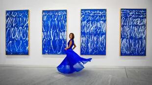 Una mujer posa frente a una parte de una serie de nueve paneles titulados "Untitled I-IX" del pintor estadounidense Cy Twembly