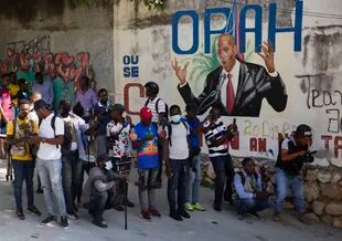 Periodistas se reúnen cerca de un mural que muestra al presidente haitiano Jovenel Moise, cerca de la residencia del líder, donde fue asesinado por hombres armados