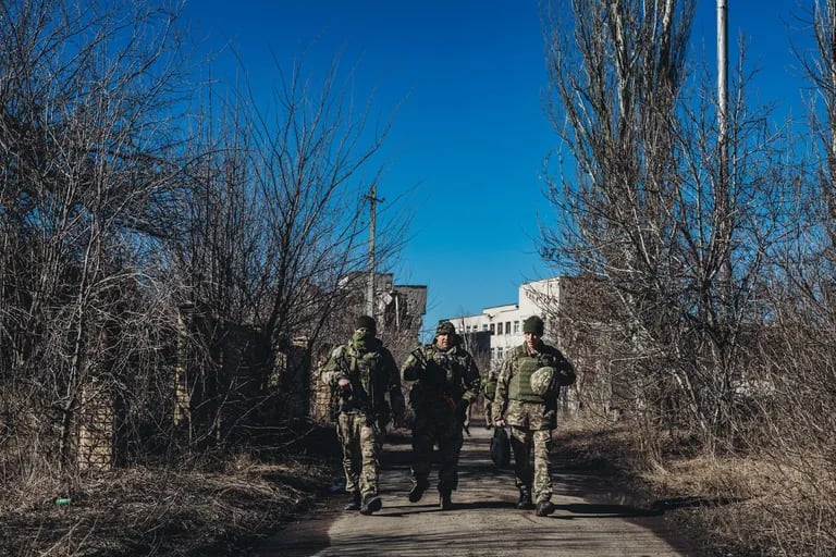 15-02-2022 Varios soldados ucranianos caminan frente a unas ruinas en un pueblo cercano a la línea de contacto, a 15 de febrero de 2022, en Marinka, Oblast de Donetsk
