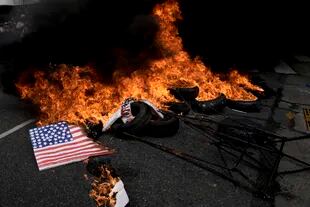 La bandera de EE. UU. se incendia junto con los neumáticos frente al Congreso de la Nación durante las protestas contra el acuerdo con el FMI