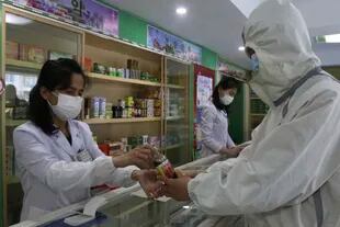Un empleado de la Oficina de Gestión de Medicamentos del Distrito de Daesong en Pyongyang proporciona medicamentos a un residente mientras el Estado aumenta las medidas para detener la propagación de enfermedades en Pyongyang, Corea del Norte, el lunes 16 de mayo de 2022.