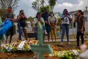 En esta foto de archivo tomada el 13 de enero de 2021, familiares de una víctima del Covid-19 asisten al funeral en el cementerio de Nossa Senhora Aparecida en Manaos