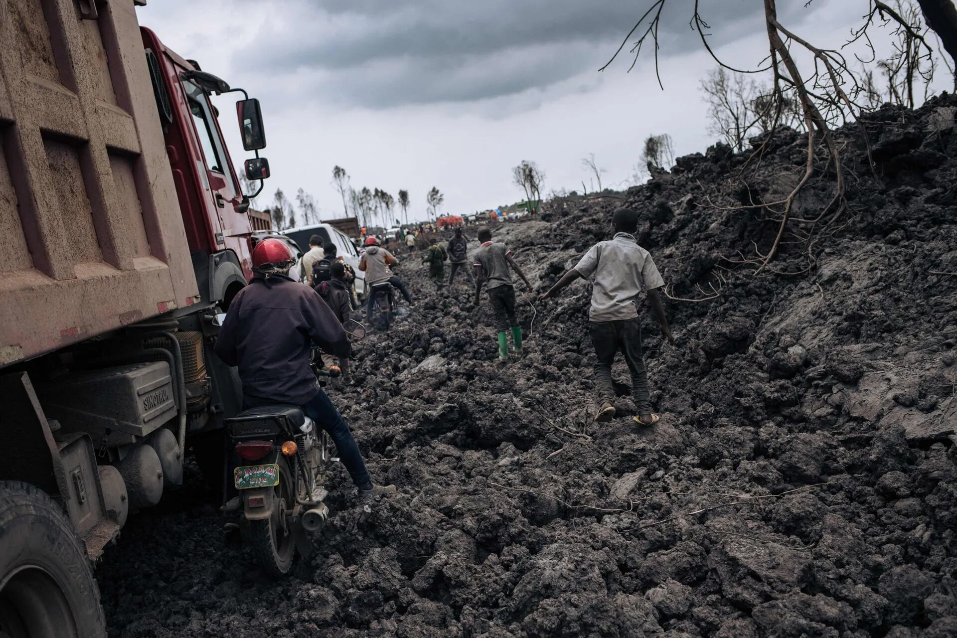 Camiones y motos intentan avanzar sobre un camino cubierto de lava solidificada del volcán Nyiragongo en los vecindarios del norte de Goma