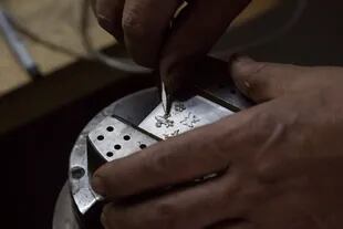 En su taller de Merlo Facundo trabaja en los detalles que llevan los cuchillos que le vende a coleccionistas del mundo entero.