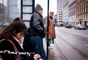 Los viajeros esperan en una parada de autobús en Copenhague el 1 de febrero de 2022, cuando Dinamarca se convierte en el primer país de la UE en levantar las restricciones de coronavirus a pesar de un número récord de casos, citando sus altas tasas de vacunación y la menor gravedad de la variante Omicron