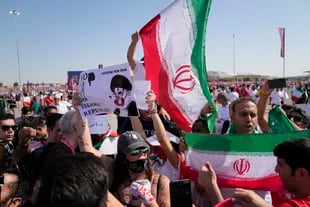 Seguidores agitan banderas iraníes y una mujer sostiene un cartel que dice "Libertad para Irán, no a la República Islámica", antes del partido de fútbol del grupo B de la Copa del Mundo entre Gales e Irán