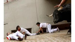 Sergio Colás, en el centro, se aleja del camino de un toro de lidia después de caer a la entrada de la plaza de toros