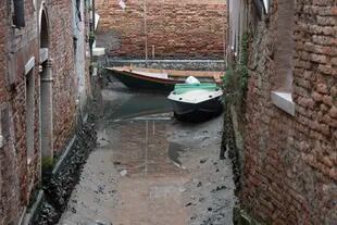 Botes atracados a lo largo de un canal seco durante una marea baja en Venecia, Italia, el martes 21 de febrero de 2023