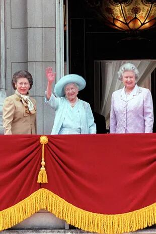 La Reina Madre de Gran Bretaña con sombrero azul y vestido celebrando su 100 cumpleaños con sus hijas: la princesa Margarita en marrón y la Reina Isabel II en lavanda en el Palacio de Buckingham..    (Photo by Ken Goff/Getty Images)