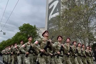 Agentes de la Guardia Nacional de Rusia marchan por una calle mientras en un edificio al fondo se ve la imagen de la letra Z, que se ha convertido en un símbolo del ejército de Rusia, el jueves 5 de mayo de 2022, en Sebastopol, Crimea