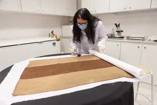 Fernanda Zigarán, la técnica que está a cargo del área de investigación del museo, en pleno proceso de limpieza de un tapiz hallado en el volcán Llullaillaco