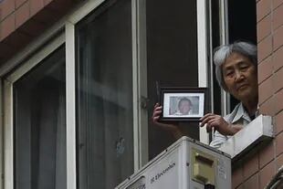 Zhang Xianling mostrando una foto de su hijo a reporteros en 2014