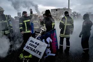 Los bomberos posan con bengalas y un esqueleto durante una manifestación en Lyon, sureste de Francia, el 19 de enero de 2023