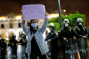 Una mujer muestra una pancarta que dice "NO al golpe" durante una protesta en una plaza principal de Lima tras el anuncio de la destitución del presidente peruano Martín Vizcarra