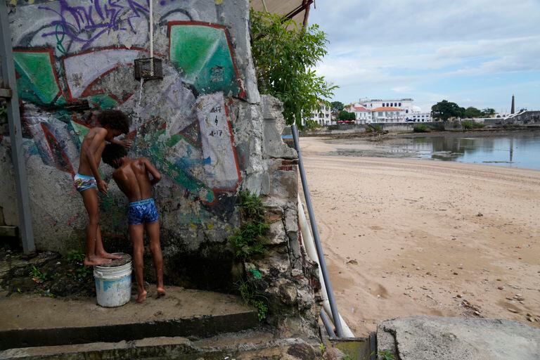 Los niños se enjuagan la arena de sus cuerpos después de pasar el día en la playa durante la celebración del Bicentenario de la independencia de Panamá de España, en el barrio Casco Antiguo de la ciudad de Panamá, el domingo 28 de noviembre de 2021. (AP Foto/Arnulfo Franco)