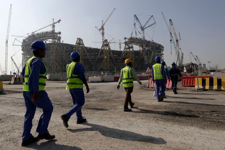 Trabajadores caminan al Estadio Lusail, uno de escenarios para el Mundial 2022
