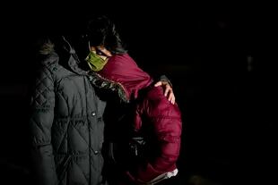 Cuban migrant Mario Perez hugs his wife as they wait to apply for asylum after crossing the border into the United States, Friday, Jan. 6, 2023, near Yuma, Arizona.  (AP Photo/Gregory Bull)