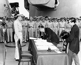 El ministro de exteriores japonés Mamoru Shigemitsu firma el Acta de Rendición de Japón a bordo del USS Missouri, mientras el general Richard K. Sutherland observa, 2 de septiembre de 1945.