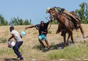 -- AFP PICTURES OF THE YEAR 2021 --A United States Border Patrol agent on horseback tries to stop a Haitian migrant from entering an encampment on the banks of the Rio Grande near the Acuna Del Rio International Bridge in Del Rio, Texas on September 19, 2021. - The United States said Saturday it would ramp up deportation flights for thousands of migrants who flooded into the Texas border city of Del Rio, as authorities scramble to alleviate a burgeoning crisis for President Joe Biden's administration. (Photo by PAUL RATJE / AFP) / AFP PICTURES OF THE YEAR 2021