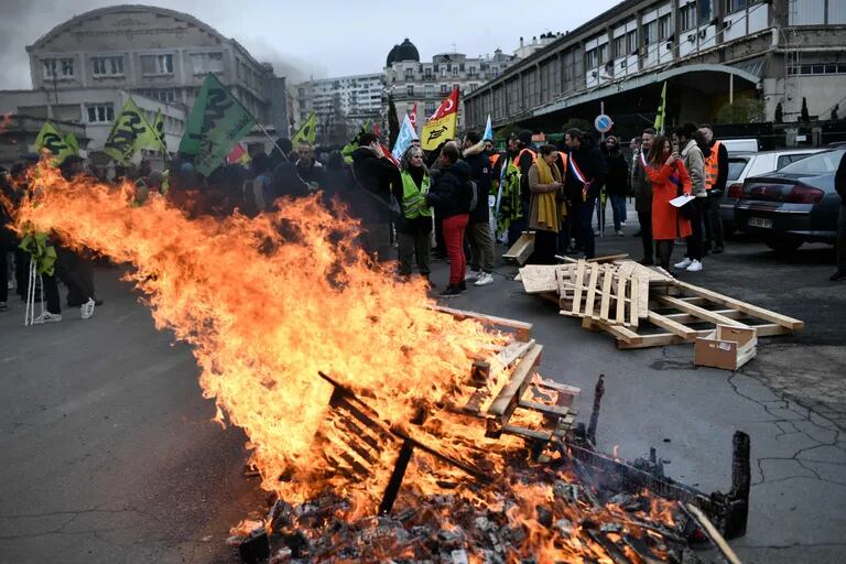 Los palets de madera arden, mientras los manifestantes se reúnen durante una manifestación convocada por los sindicatos franceses en las afueras de la Gare de Lyon, en París, el 19 de enero de 2023