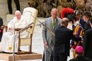 Un grupo de personas ayuda a un guardia suizo a levantarse después de que se desmayara durante la audiencia general semanal del Papa Francisco el 17 de agosto de 2022 en la sala Pablo-VI del Vaticano.