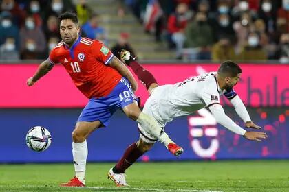 Luis Jiménez y  Tomás Rincón luchan por la pelota durante el partido de eliminatorias de la Copa del Mundo Qatar 2022 que disputan Chile y Venezuela