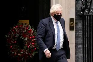 El primer ministro británico Boris Johnson sale de la residencia oficial de 10 Downing Street para asistir a la sesión semanal de preguntas en la Cámara de los Comunes, Londres; tras él, el escándalo. (AP Foto/Matt Dunham)