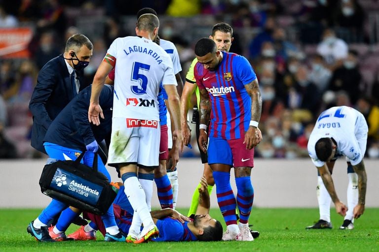 Los médicos asisten al delantero argentino del Barcelona Kun Agüero (ABAJO) tras resultar lesionado durante el partido de fútbol de la Liga española entre el FC Barcelona y el Deportivo Alaves en el estadio Camp Nou de Barcelona el 30 de octubre de 2021