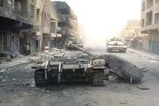 Un tanque M1A1 Abrams norteamericano pasa ayer delante de blindados iraquíes destruidos durante la primera incursión aliada a Bagdad