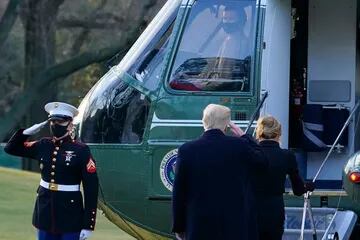 El presidente saliente Donald Trump saluda mientras aborda el Marine One con la primera dama Melania Trump