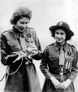La reina Isabel II, cuando aún era princesa, mostrándole a su hermana Margaret una de las palomas mensajeras.