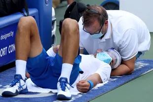 Novak Djokovic, atendido por el fisioterapeuta en una interrupción de su partido con Roberto Bautista Agut: barbijo y máscara.