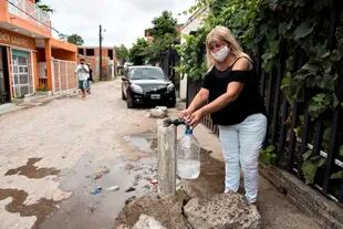 Miriam llena un bidón con agua potable que sale de una canilla comunitaria cercana a su casa