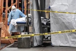 Un trabajador de un hospital en Brooklyn retira el cuerpo de un fallecido del establecimiento para llevarlo a un camión refrigerado