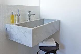 En el baño, revestimiento de venecitas blancas, bacha de mármol y banco de hierro (Landmark).