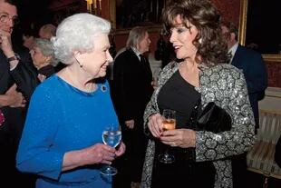 En una recepción celebrada en el Palacio de Buckingham, el 17 de febrero de 2014, conversa con la actriz Joan Collins.