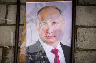 FILE - A portrait of Russian President Vladimir Putin lies on the ground with his frame broken near a local prison in Jershon, Ukraine, Wednesday, Nov. 16, 2022. Putin avoided mentioning the withdrawal of Russian troops from Jershon.  A humiliating withdrawal for its army in Ukraine.  (AP Photo/Efrem Lukatsky, File)