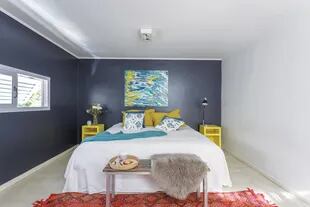 Más allá de la clásica del respaldo, en esta suite el azul oscuro conquistó dos paredes en ángulo. El contraste lo dan un par de mesitas de luz amarillas (Carlos Méndez) y el cuadro de Nora Maneiro. 